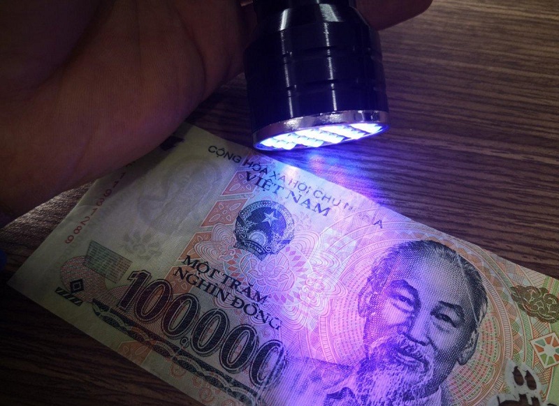 Có thể phân biệt tiền thật giả bằng đèn tia cực tím
